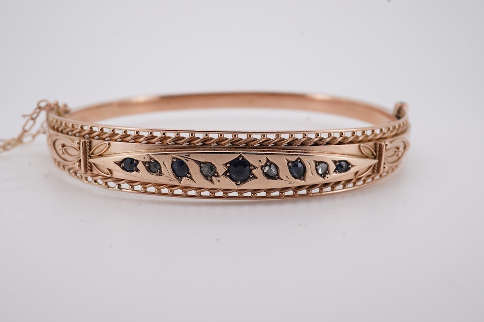 An Edwardian 9ct gold, sapphire and diamond set hinged bangle, Chester, 1909, interior diameter 57mm, gross weight 10 grams. Condition - poor